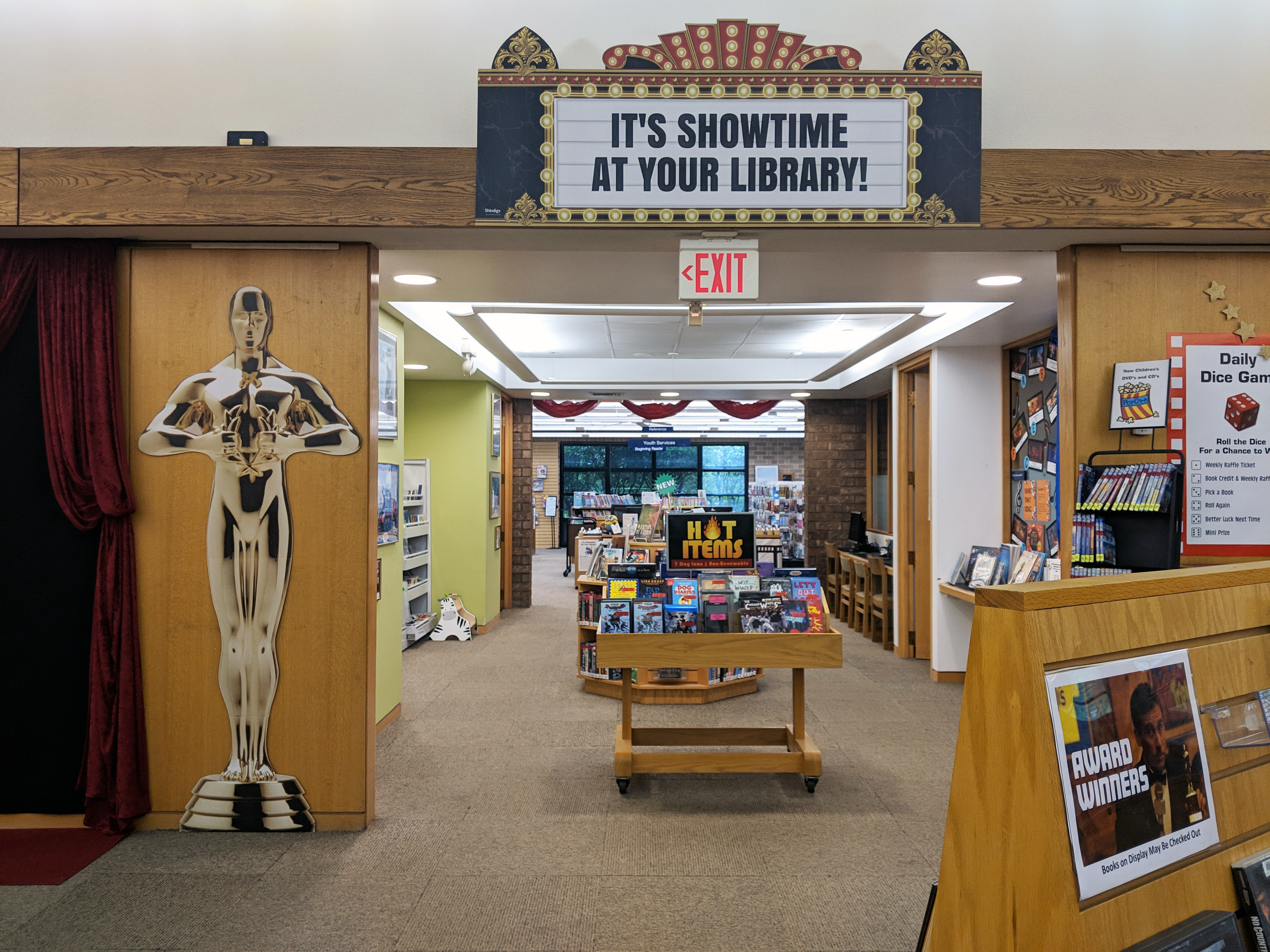 Entrance of the library adorned with cutouts of the Oscars statue and a movie theatre marquee that reads, "It's Showtime at your Library"