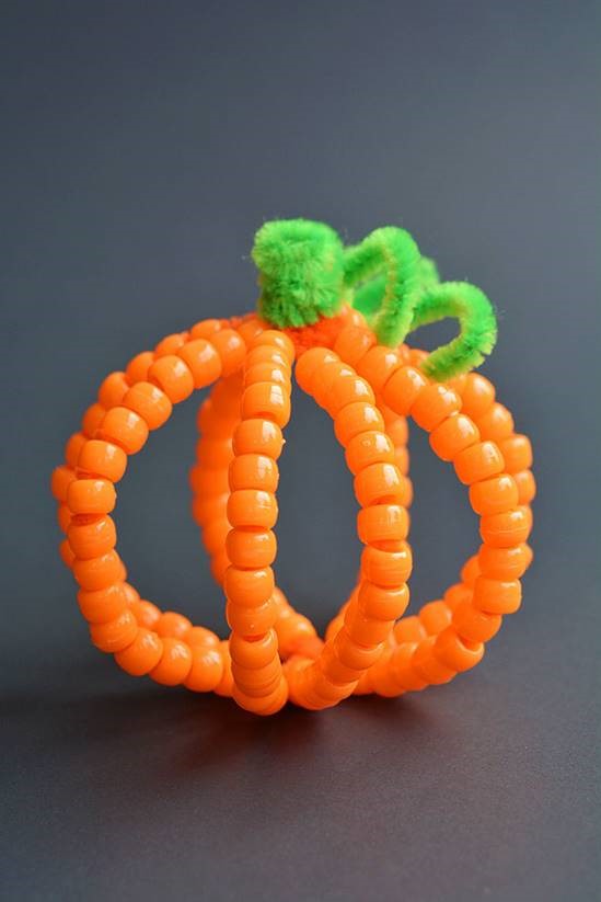 orange beads on orange pipe cleaners arranged in teh shape of a pumpkin