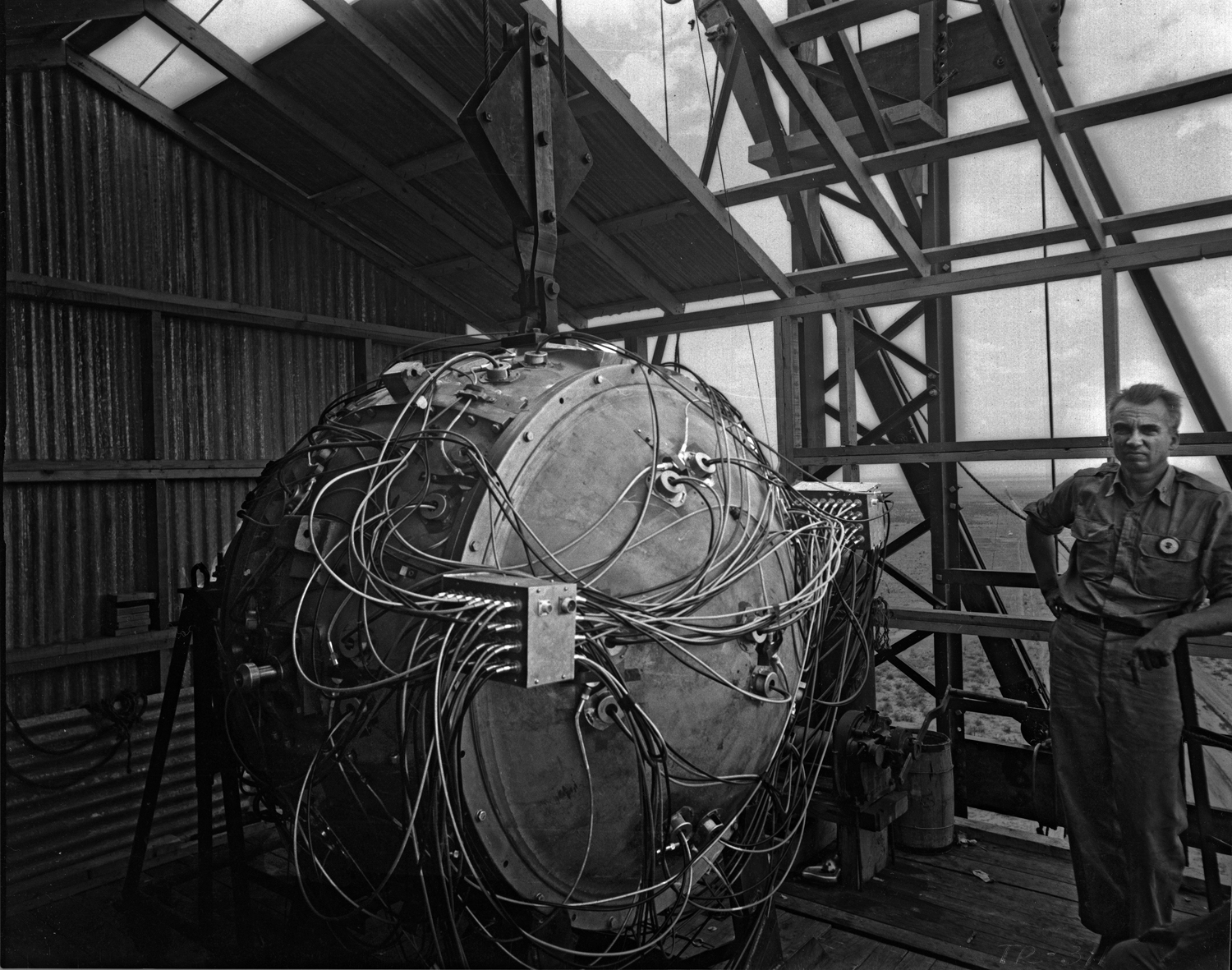 The assembled implosion “gadget” of the Trinity test, July 1945, with physicist Norris Bradbury for scale