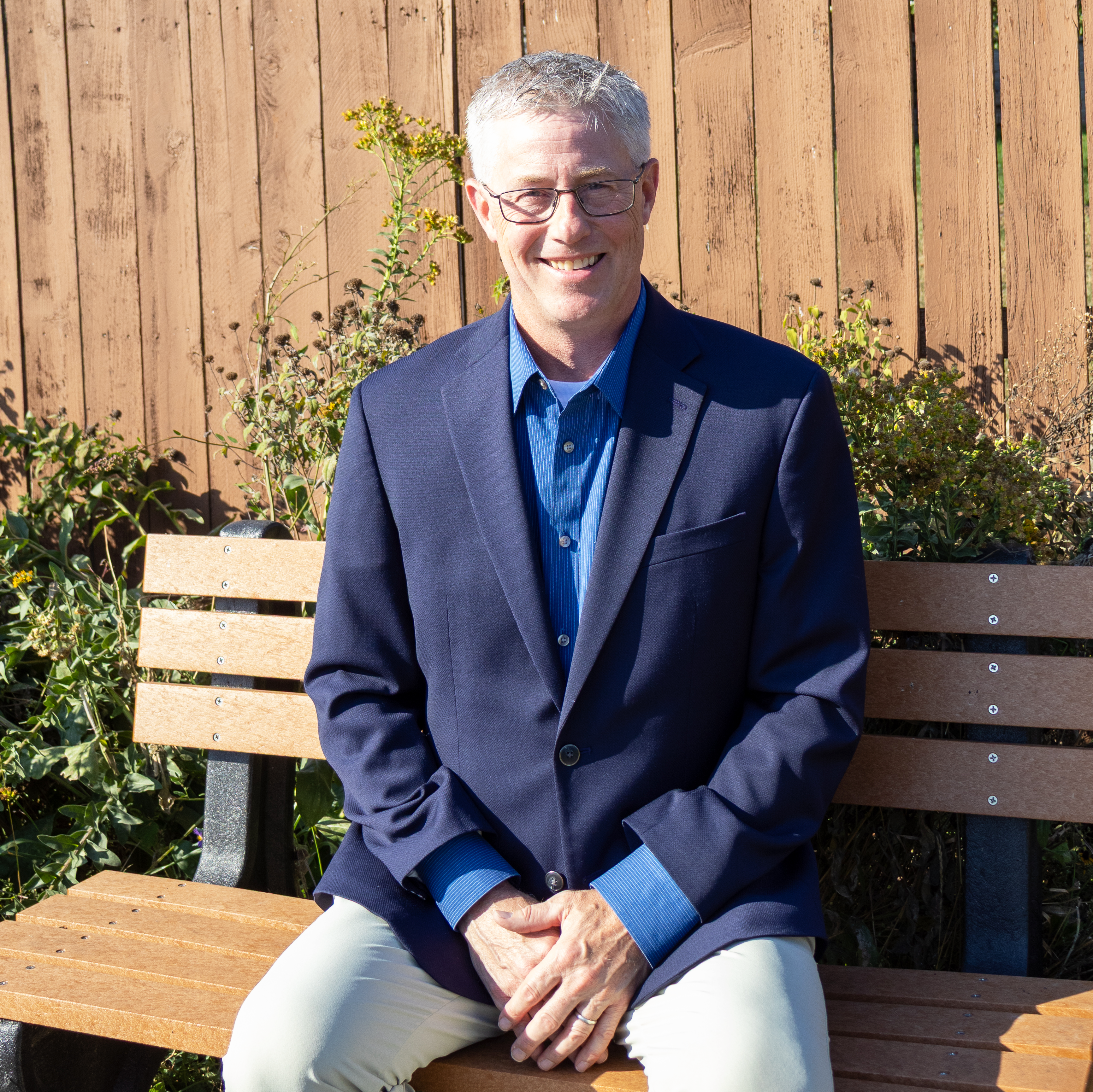 Photo of Bill Moser our Board Vice President sitting in a chair smiling at the camera.