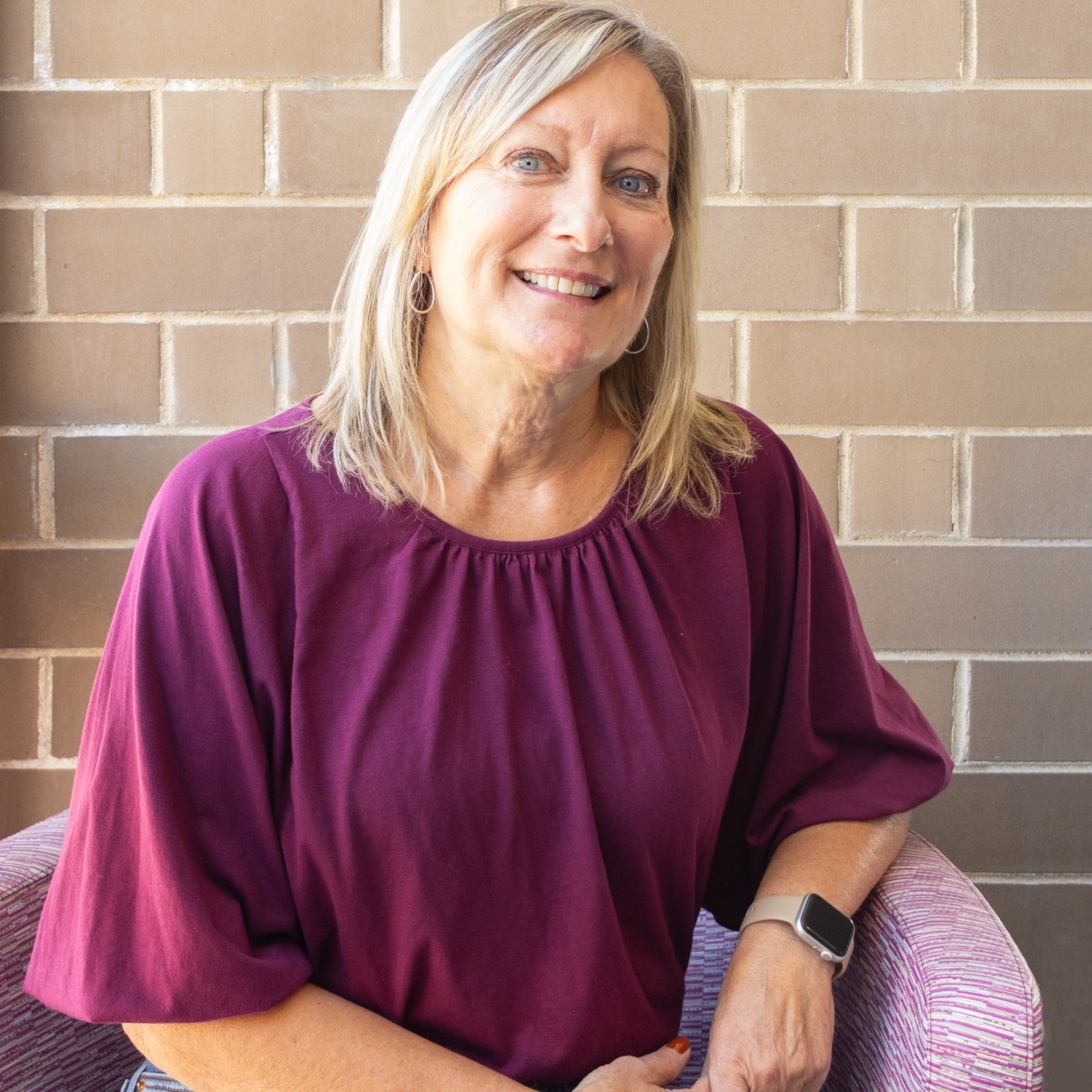 Photo of Janet Jordan our Board Secretary sitting in a chair smiling at the camera.