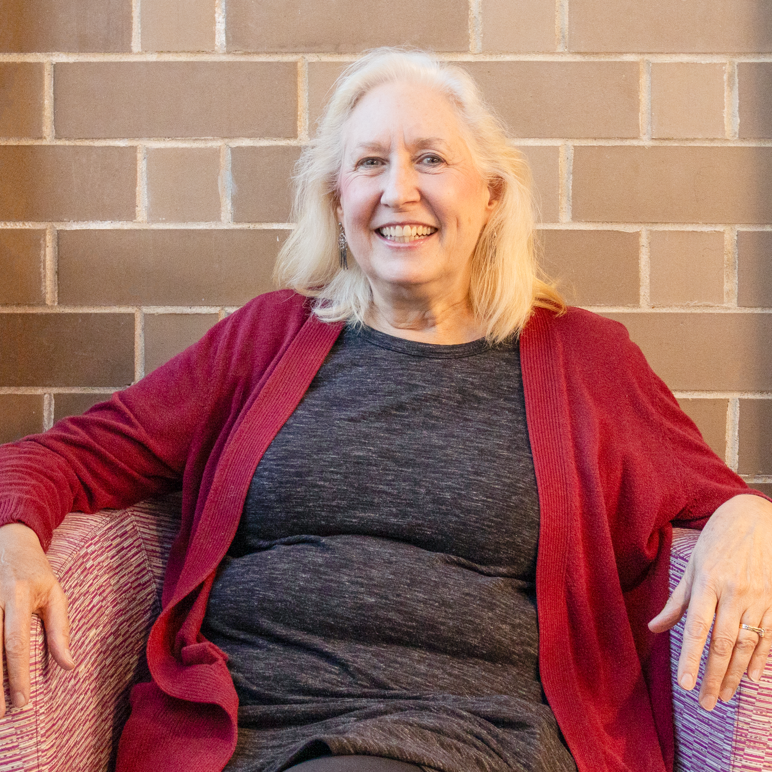 Photo of Marianne Kerr our Board President sitting in a chair smiling at the camera.