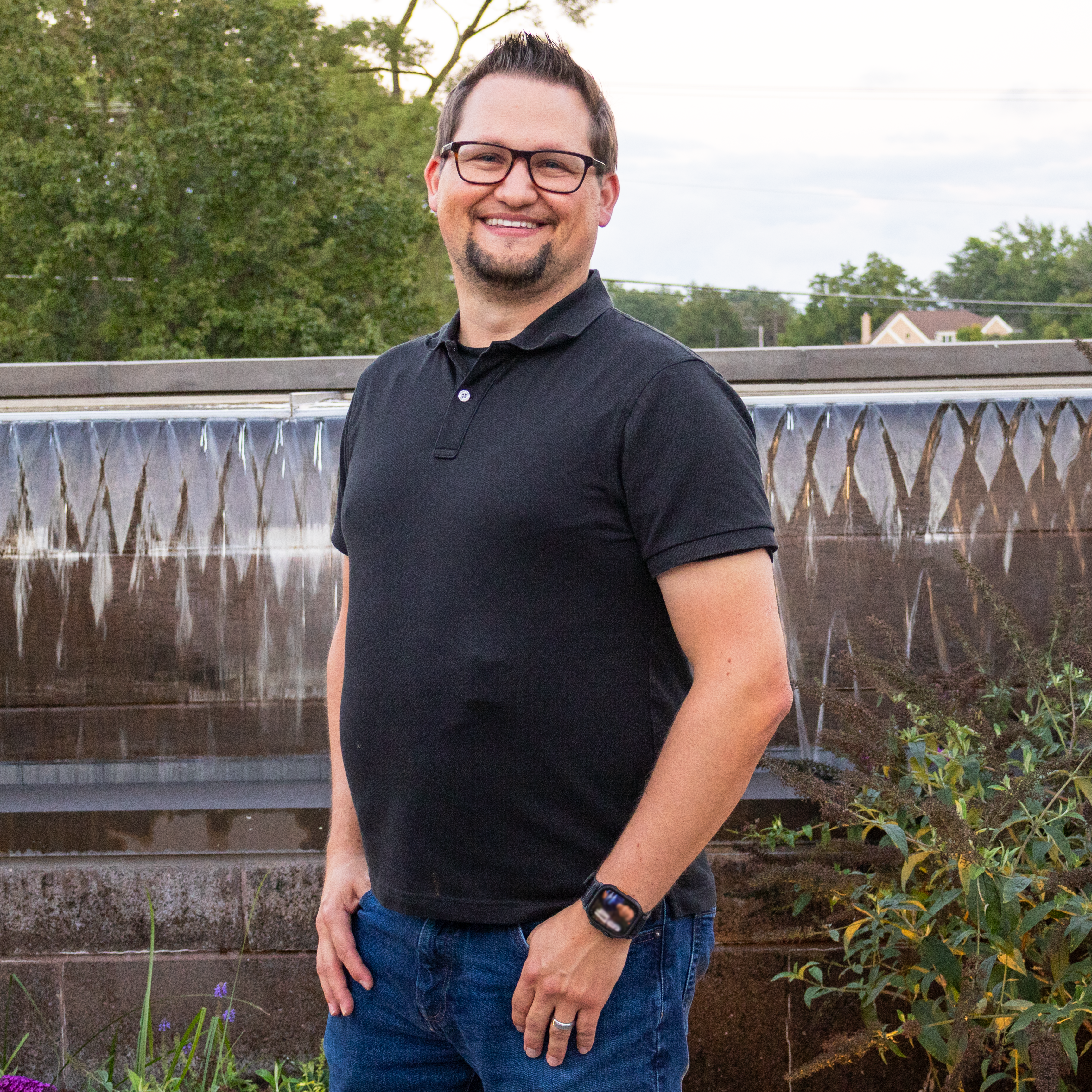 Photo of Tim Bochula our Board Member standing by our fountain smiling at the camera.