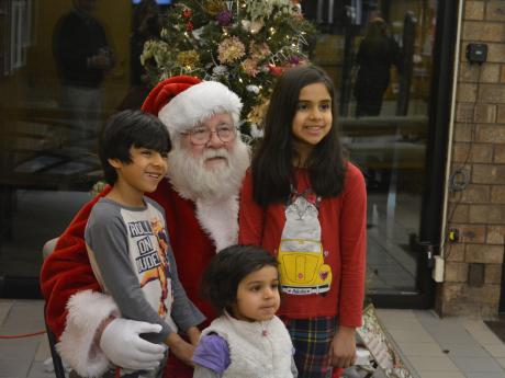 Siblings posing with Santa during the Family Gingerbread Craft event