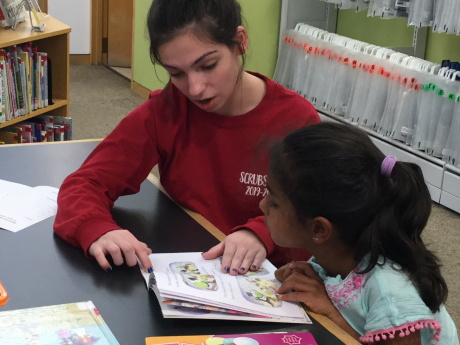 Teen volunteer reading to child 