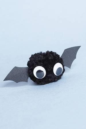 a yarn ball with google eyes and paper wings