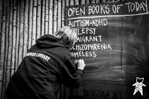 Person writing on a chalk board a list of available Books