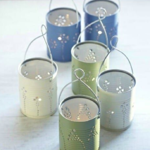 six green and blue tin cans with designs stamped into them on a gray background