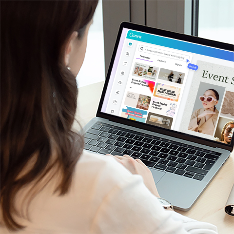 a woman viewed from behind over her shoulder. In front of her is a laptop opened to the Canva website, showing some of the editing options