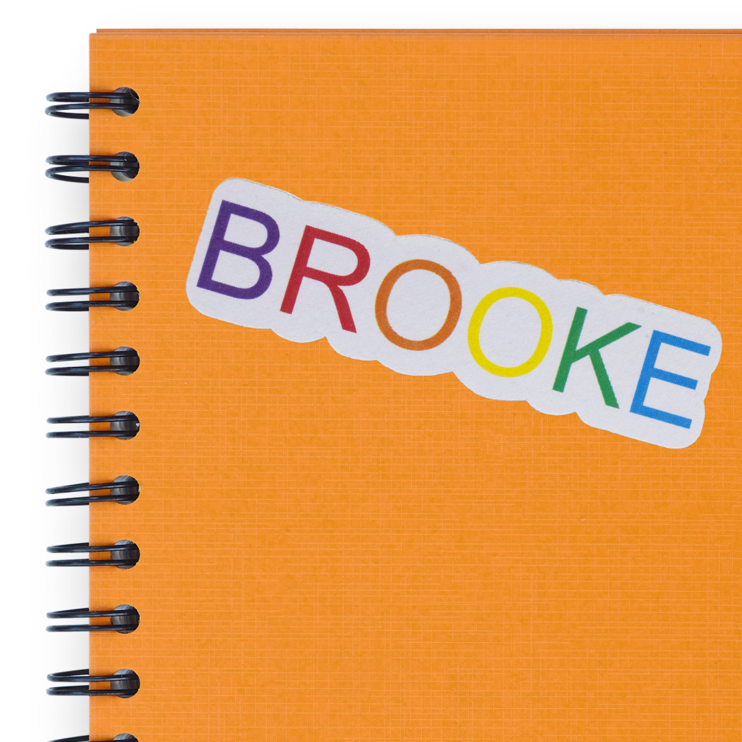 Orange notebook with a name sticker in rainbow colors.